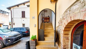 A building with a staircase leading to an entrance, parked cars, and a visible number '57' on the wall. - Vrbo Property (Foligno)