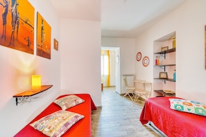 A room with two beds, a table, chairs, and artwork on the walls. - Vrbo Property (Foligno)