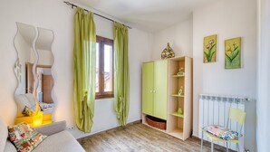 A room with a sofa, a green cabinet, a chair, a radiator, and artwork on the wall. - Vrbo Property (Foligno)