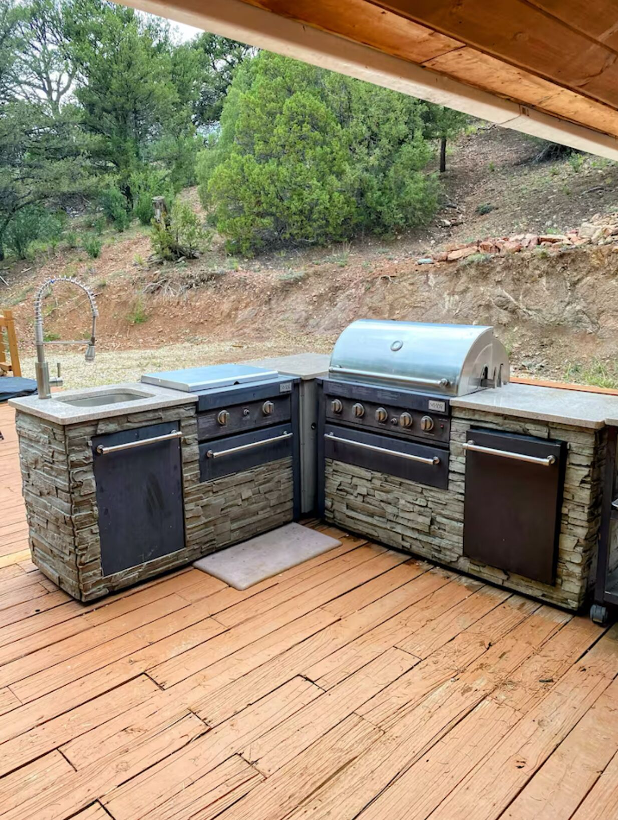 An outdoor kitchen with a stone countertop, a built-in sink, and a grill.