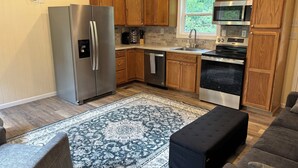 Une cuisine moderne avec des meubles en bois, des appareils électroménagers en acier inoxydable et un grand tapis.