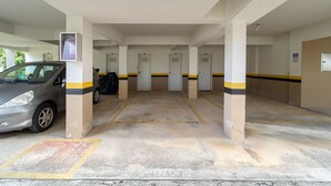 A parking garage with multiple doors, a car parked on the left, and a sign on the wall. - Apt 700m From Ingleses Beach Mab0203 (Florianópolis)