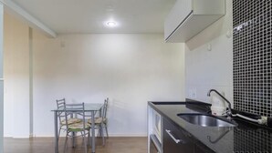 A compact kitchen with a dining table and chairs, a sink, and a tiled backsplash. - Apt 700m From Ingleses Beach Mab0203 (Florianópolis)