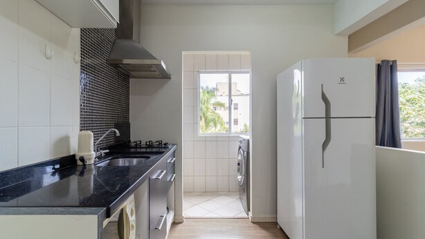 A compact kitchen with a black countertop, stainless steel appliances, and a window providing a view of the outside. - Apt 700m From Ingleses Beach Mab0203 (Florianópolis)