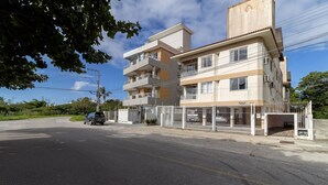 A multi-story residential building with balconies, a gated parking area, and a clear sky. - Apt 700m From Ingleses Beach Mab0203 (Florianópolis)