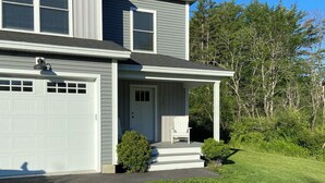 A two-story house with a garage, a covered porch, and a well-maintained lawn.