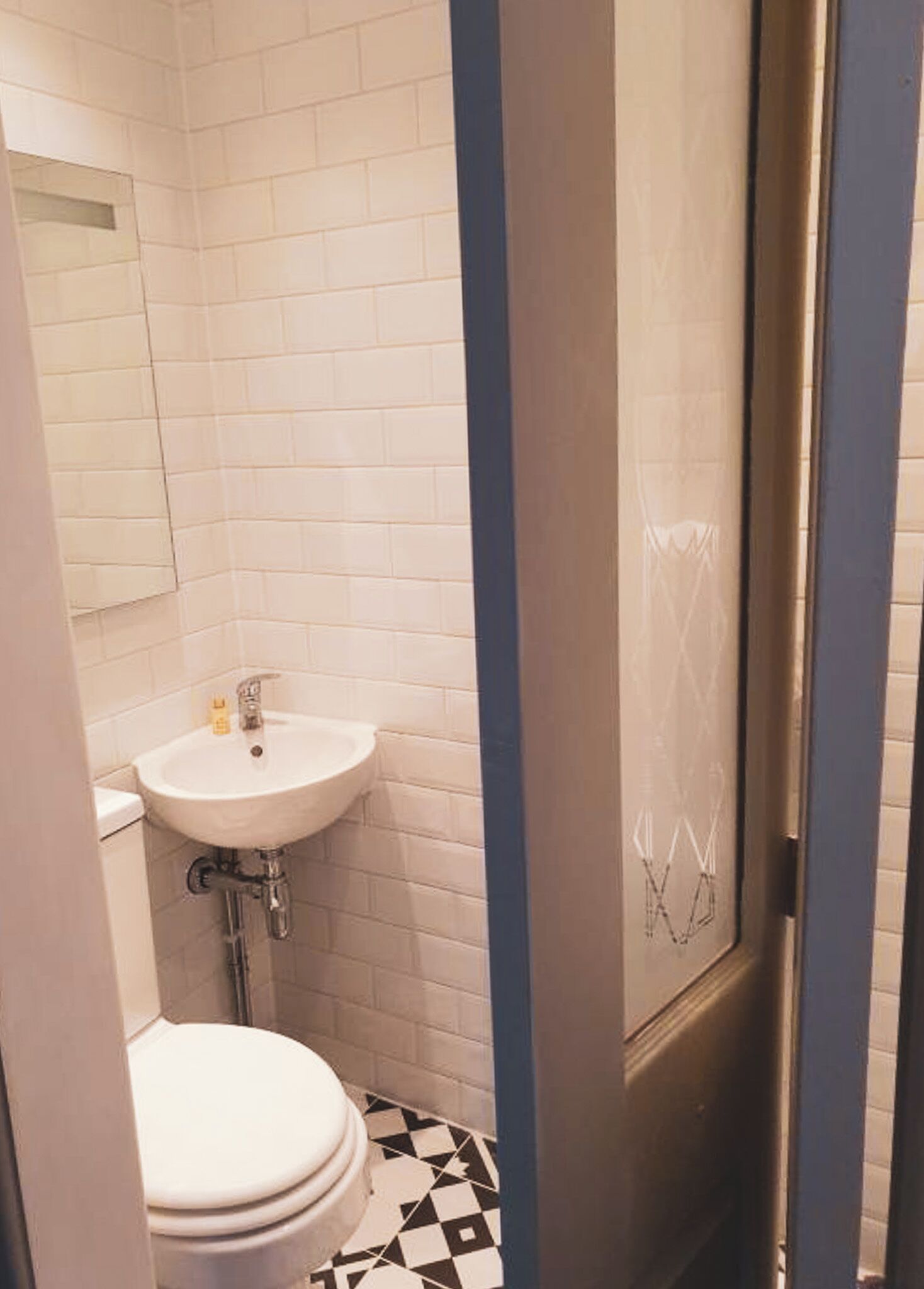 A small bathroom with a white sink, a toilet, and a shower area.