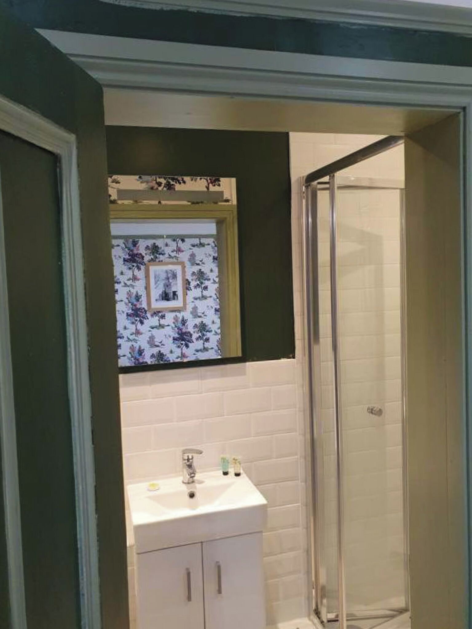 Un baño con un lavabo blanco, un espejo encima y una cabina de ducha de vidrio.