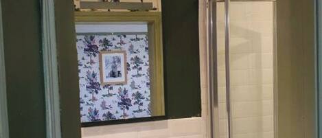 Un baño con un lavabo blanco, un espejo encima y una cabina de ducha de vidrio.