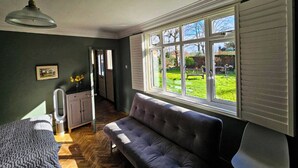A room with a large window, a sofa, a bed, and a ceiling fan. - The Lodge Stanwell (Staines)