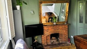 A room with a fireplace, a large mirror, a television, and a bench. - The Lodge Stanwell (Staines)