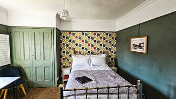 A bedroom with a bed, a desk, and a chair.