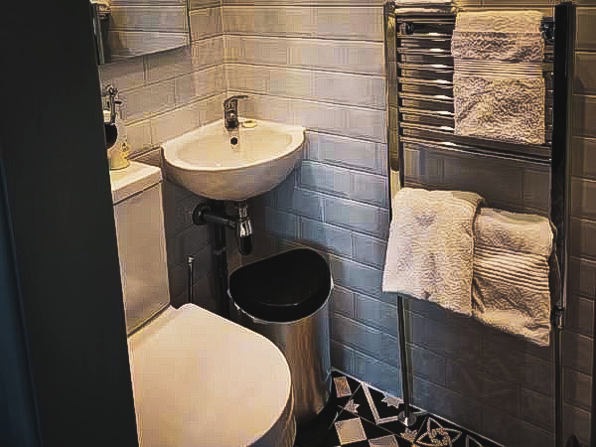Un baño pequeño con lavamanos, inodoro y perchero para toallas.