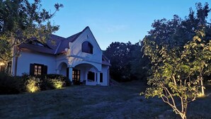 A large, single-story house with a sloped roof and a covered porch. - Villa a Balaton-Felvidéken, ahol jakuzziban gyönyörködhet a tó panorámájában (Vászoly)