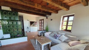 A cozy living room with a wooden ceiling, a white sofa, a wooden coffee table, and a green decorative wall. - Villa a Balaton-Felvidéken, ahol jakuzziban gyönyörködhet a tó panorámájában (Vászoly)