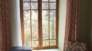 A room with a large window, a wooden chair, and a small table.