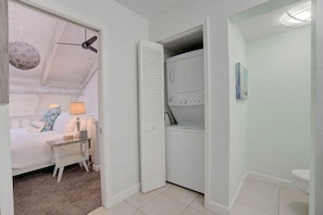 Ein Schlafzimmer mit Bett, Nachttisch, Lampe und Deckenventilator.