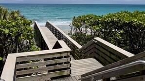 A wooden boardwalk leading to a beach with clear skies and calm sea. - Beachside townhouse with private office space (Jupiter)