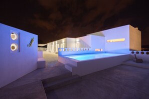 A modern outdoor pool area with steps leading to a pool, surrounded by white walls and minimalist design elements.