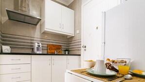 A modern kitchen with white cabinets, a stainless steel range hood, and a striped backsplash. - Mar Alta - Estelas (Peniche)