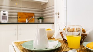 A breakfast setting with a pitcher, a glass of orange juice, and a bowl of fruit on a woven mat. - Mar Alta - Estelas (Peniche)