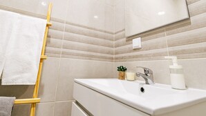 A bathroom with a white sink, a mirror, a towel rack, and a small plant. - Mar Alta - Estelas (Peniche)