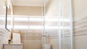 Ein modernes Badezimmer mit Duschkabine aus Glas, Toilette und Waschbecken. Ein Handtuch hängt an der Wand.