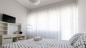 Ein Schlafzimmer mit einem Bett, einem Schreibtisch, einem Fernseher und einer Pendelleuchte.