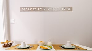 Ein Esstisch mit Unterlage, einer Schüssel mit Frühstücksflocken, einem Glas Milch und einem Teller mit Obstscheiben.