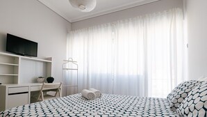 A bedroom with a bed, a desk, a television, and a hanging light fixture. - Mar Alta - Baleal in Peniche (Peniche)
