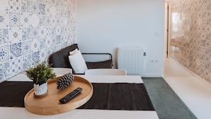 A modern room with a bed, a small table with a plant and remote control, and patterned walls. - Encosta d Bidos T1 (Obidos)