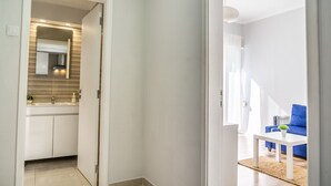 A modern apartment with a kitchen, a living area with a blue sofa, and a view of the outdoors. - Mar Alta - Gamb a (Peniche)