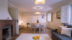 Ein gemütliches Wohnzimmer mit Kamin, einem Essbereich mit Tisch und Stühlen sowie einer Couch mit Kissen.