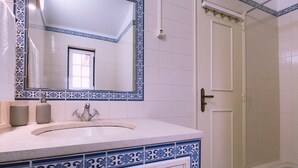 Ein Badezimmer mit einem weißen Waschbecken, einem Spiegel und einer Dusche.