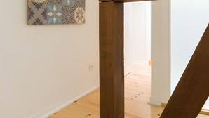Ein Zimmer mit Holzboden, weißer Wand und einem gemusterten Kunstwerk.