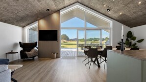 A spacious room with a large window, a wooden ceiling, and a modern kitchen area. - Stunning home in Sæby with sauna (Sæby)
