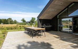 An outdoor patio with a wooden deck, a table with chairs, and a barbecue grill. - Stunning home in Sæby with sauna (Sæby)