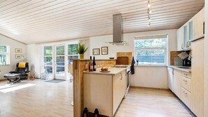 A spacious kitchen with wooden flooring, a central island, and large windows offering views of the outdoors.