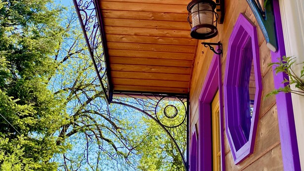 A wooden building with a purple and yellow exterior, a metal spiral staircase, and a hanging lantern. - Cozy caravan in Mississippi area of Portland with WiFi, AC (Portland)