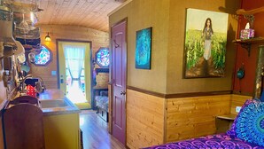 A cozy room with a bed, a wooden wall, a painting, and a kitchen area with a sink and stove. - Cozy caravan in Mississippi area of Portland with WiFi, AC (Portland)
