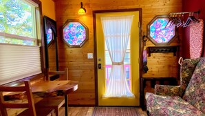A wooden cabin interior with a dining table, a sofa, and a door with stained glass windows. - Cozy caravan in Mississippi area of Portland with WiFi, AC (Portland)