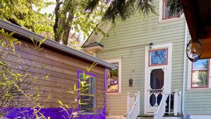 A backyard with a stone pathway leading to a wooden deck, surrounded by potted plants and a purple fence. - Cozy caravan in Mississippi area of Portland with WiFi, AC (Portland)