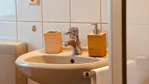 Un lavamanos con grifo, dos dispensadores de jabón de madera y un inodoro.
