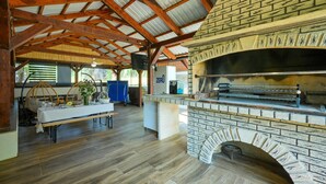 A rustic dining area with a brick oven and a table set for a meal. - Pet friendly home in Bjelovar with sauna (Curlovac)