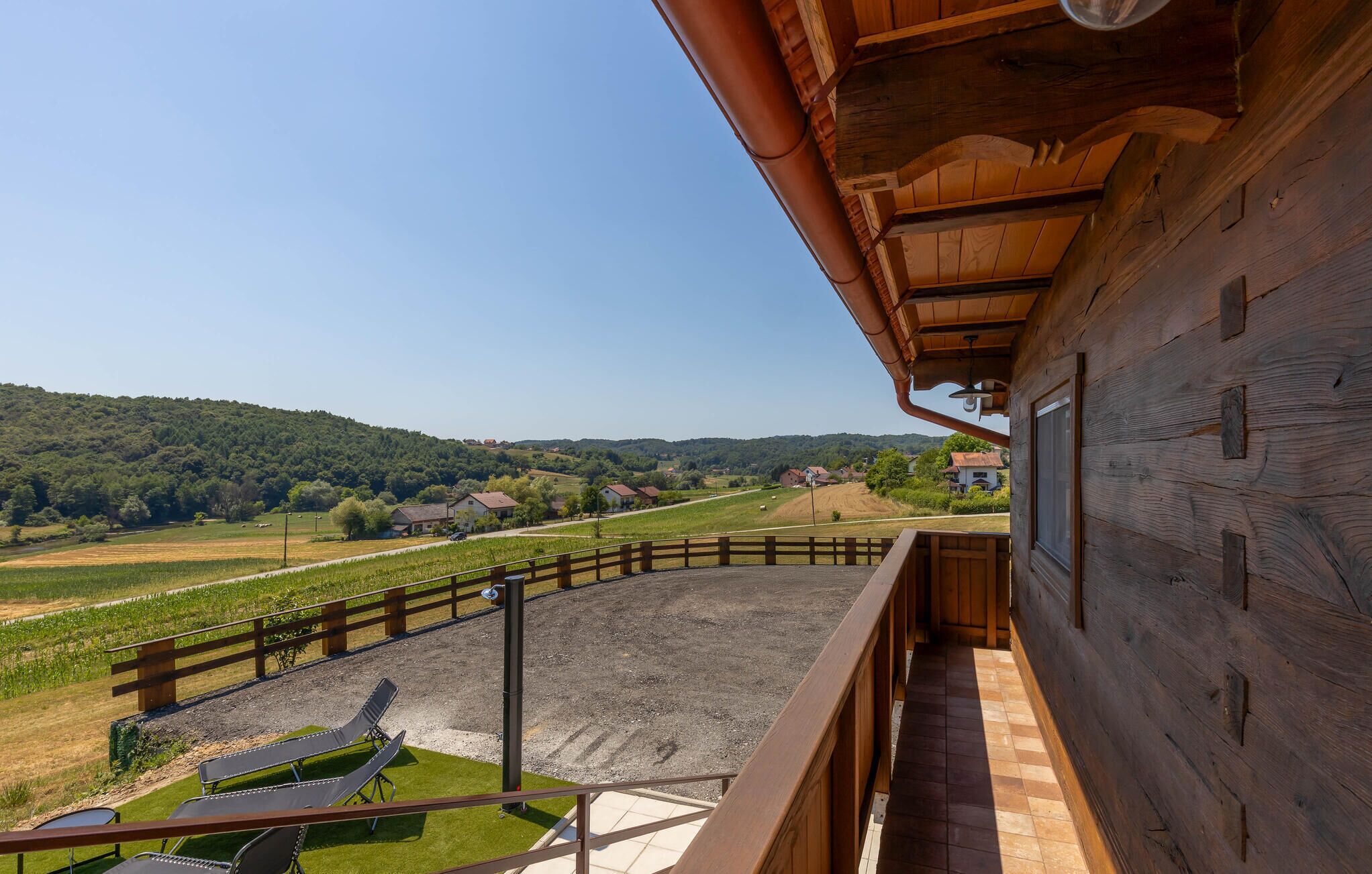 Un bâtiment en bois doté d’un balcon donnant sur un paysage rural.