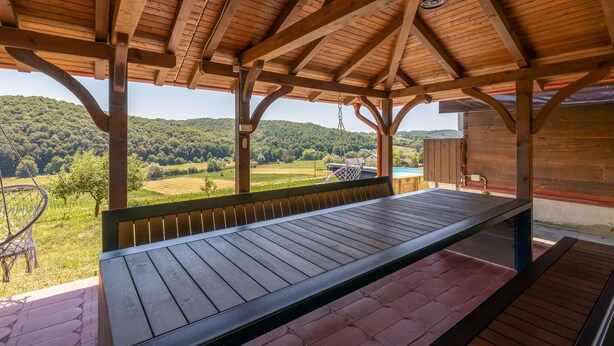 A covered outdoor seating area with a wooden bench and a view of a green landscape. - Awesome home in Jaskovo with heated swimming pool (Jaskovo)