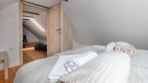 A bedroom with a bed, a wooden door, a small table, and a view of an adjacent room with a ceiling light. - Awesome home in Jaskovo with heated swimming pool (Jaskovo)