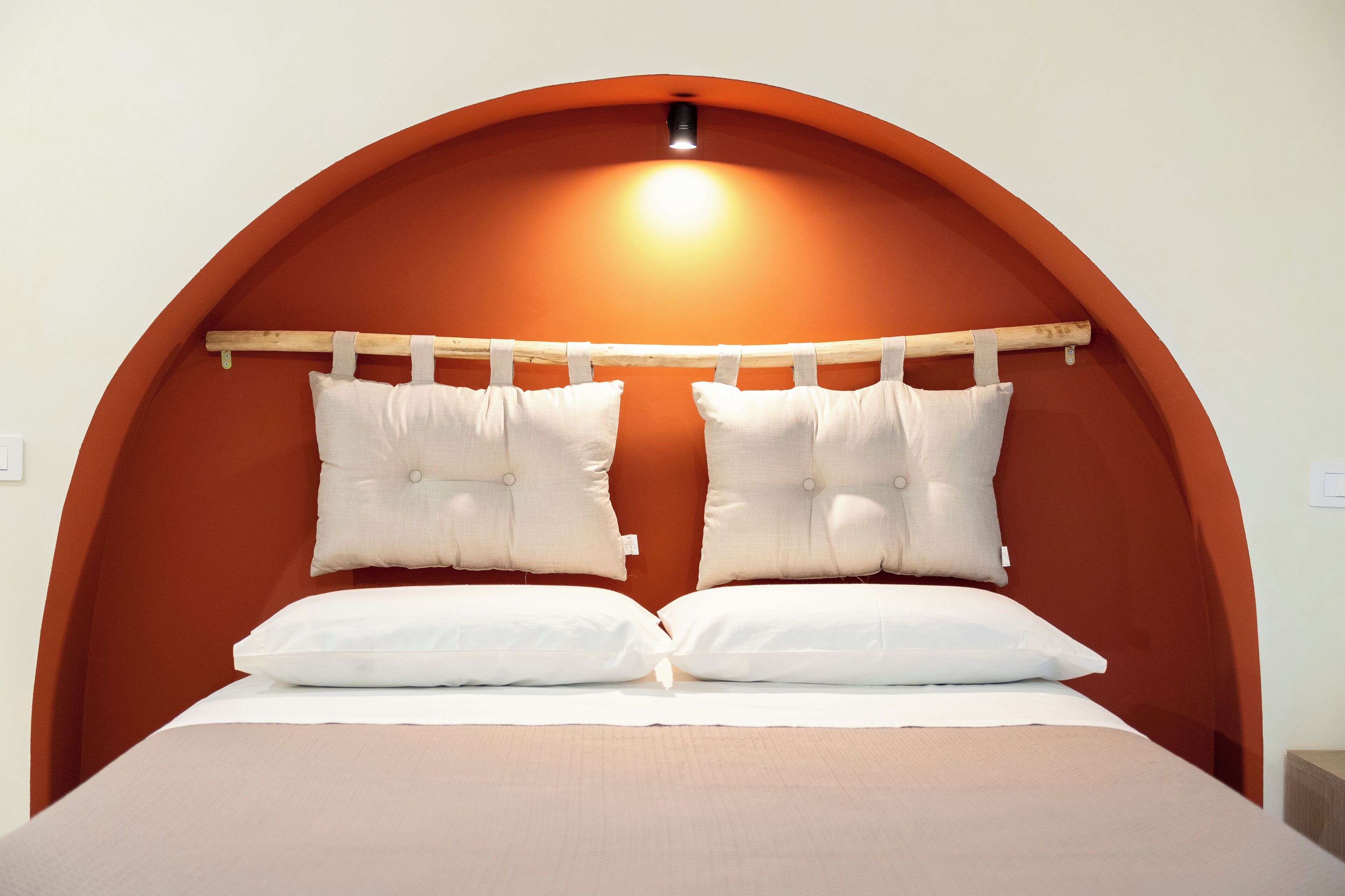 A bed with a curved headboard, two pillows, and a wooden headboard support.