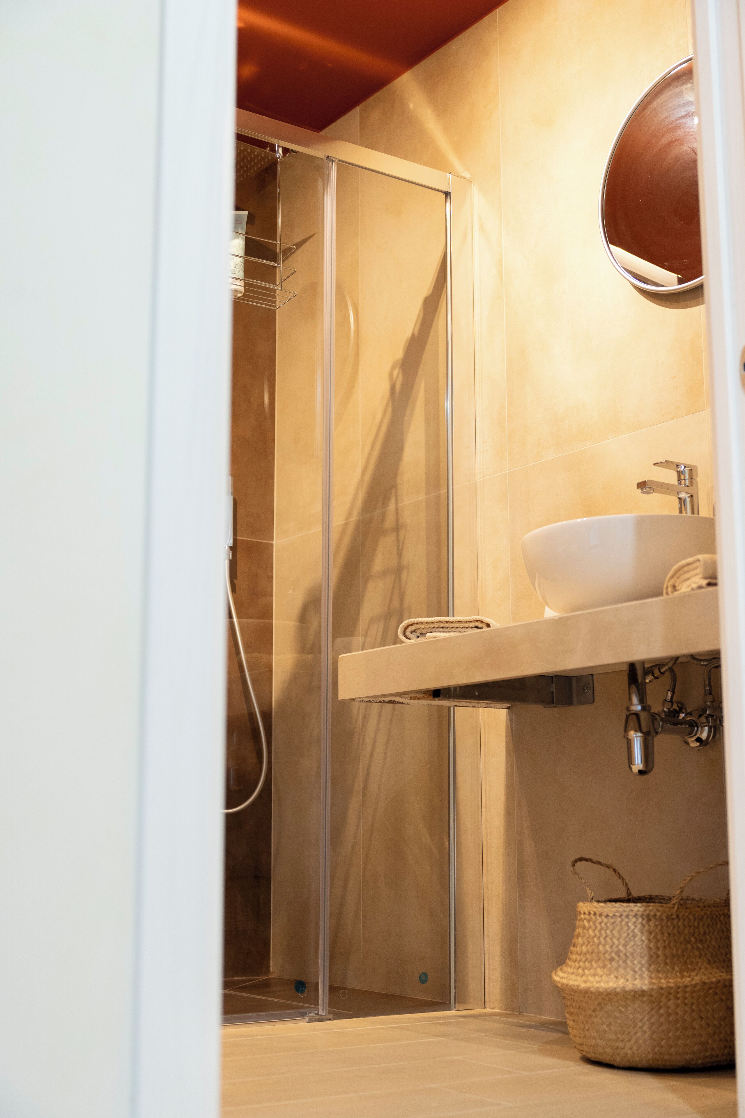 Een moderne badkamer met een douchecabine van glas, een witte wastafel en een spiegel erboven.
