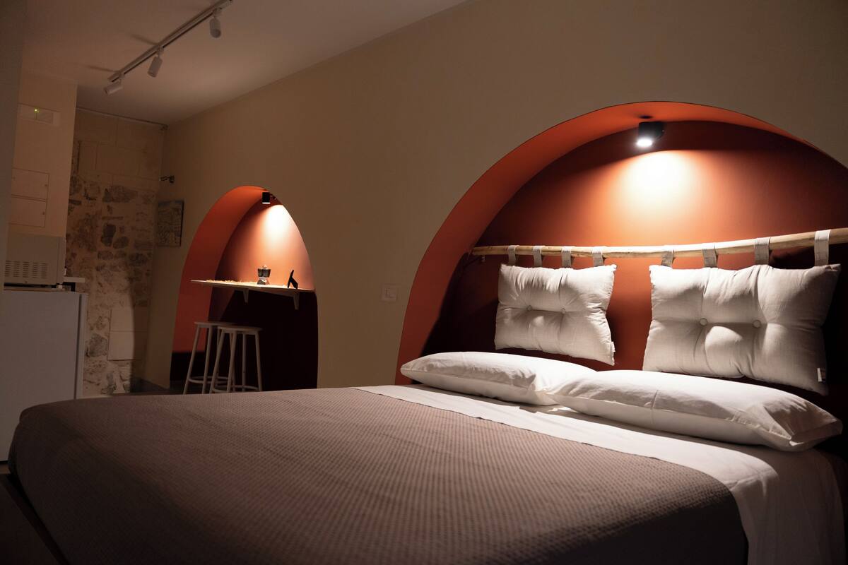 A hotel room with a large bed, a desk, and a chair.